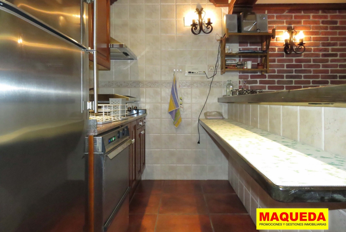 Zona interior de barra y cocina equipada con electrodomésticos
