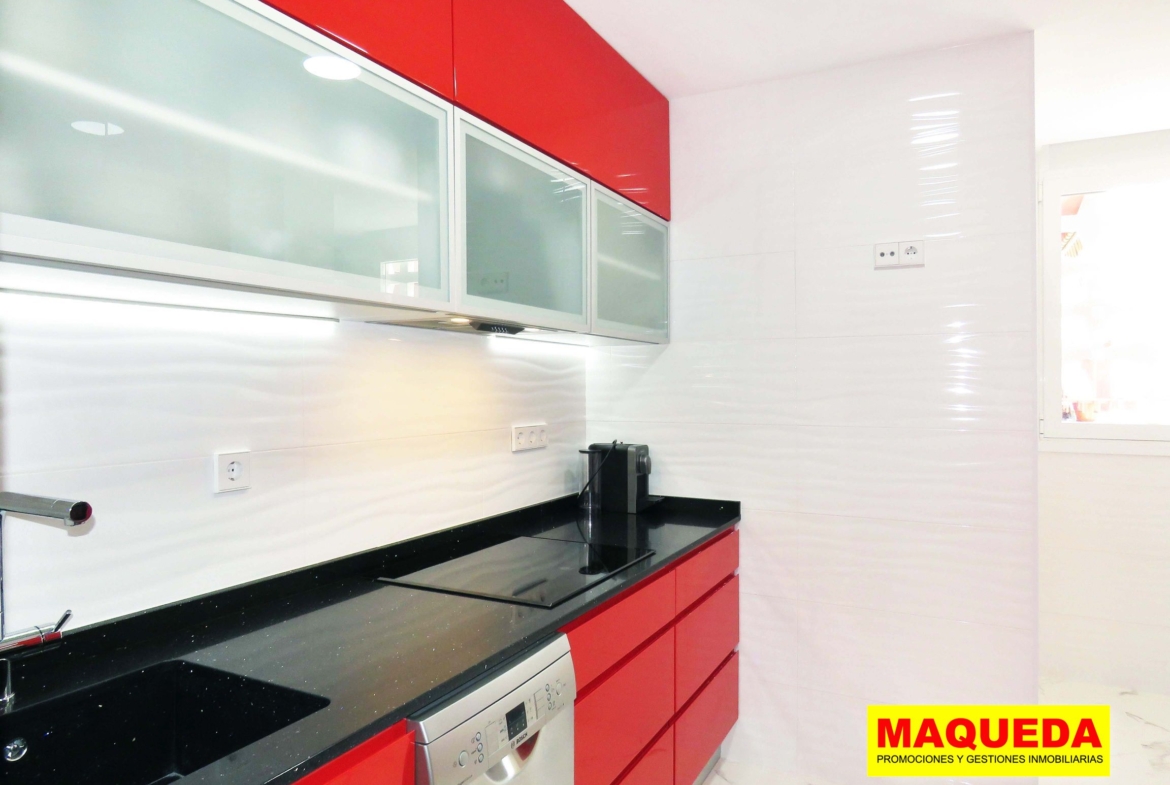 Cocina con muebles rojos y encimera de granito negro