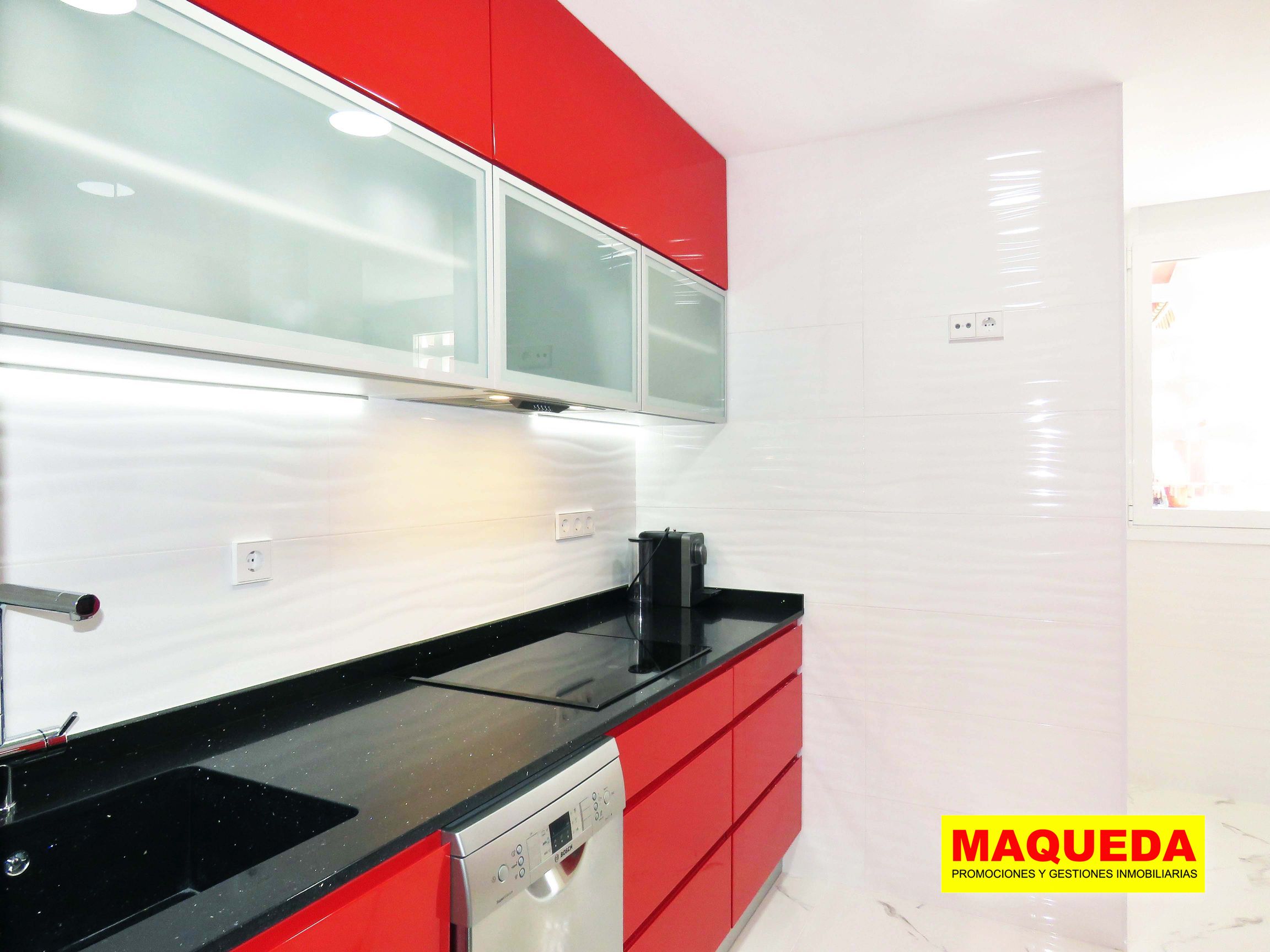 Cocina con muebles rojos y encimera de granito negro