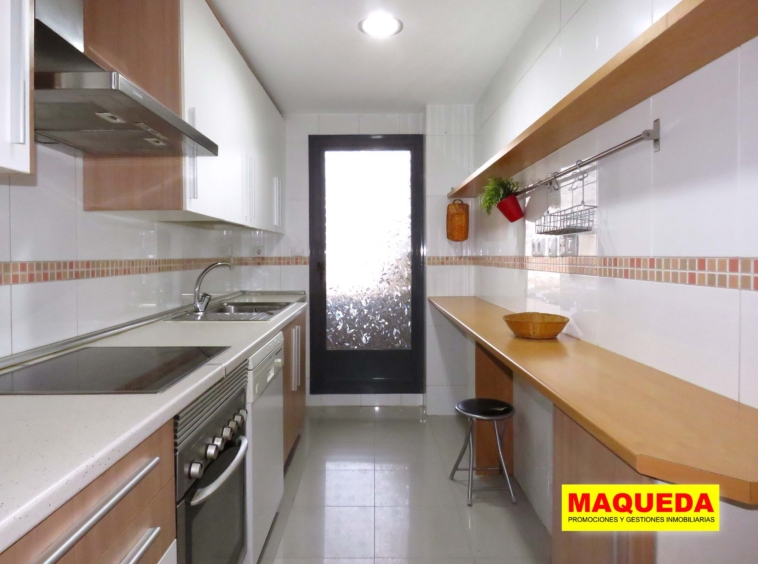 Cocina amueblada en tonos madera y blanco con tendedero al fondo