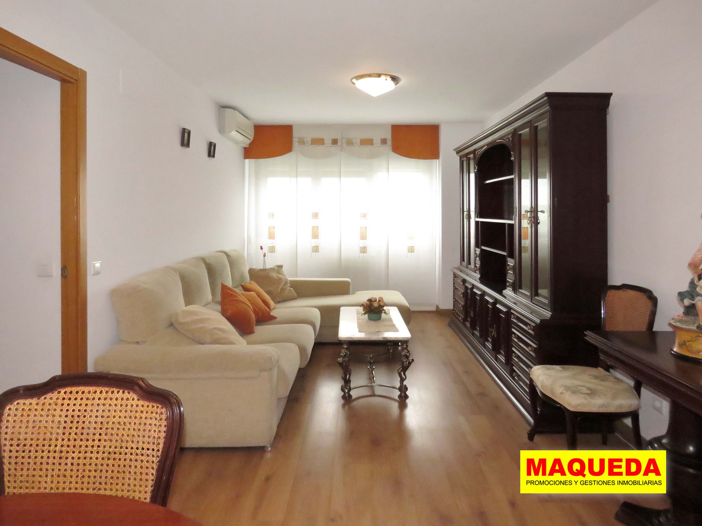 Salón con sofá chaiselongue, mueble de madera y mesa baja