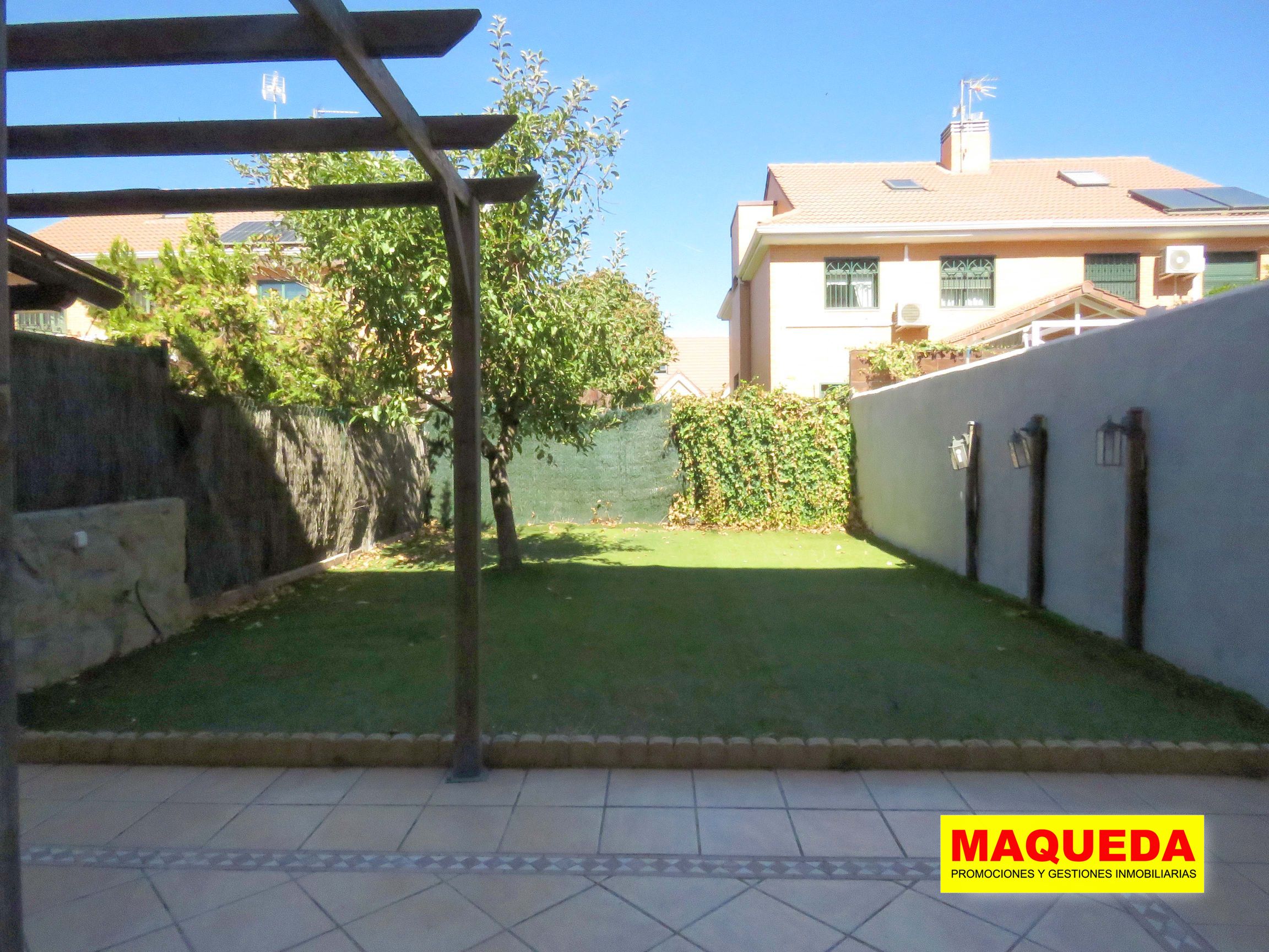 Jardín con pérgola de madera y césped artificial