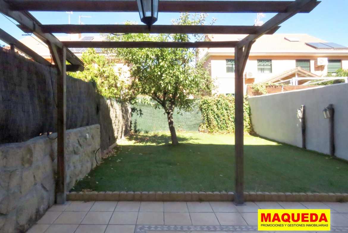 Jardín con pérgola de madera, césped artificial y árbol frutal