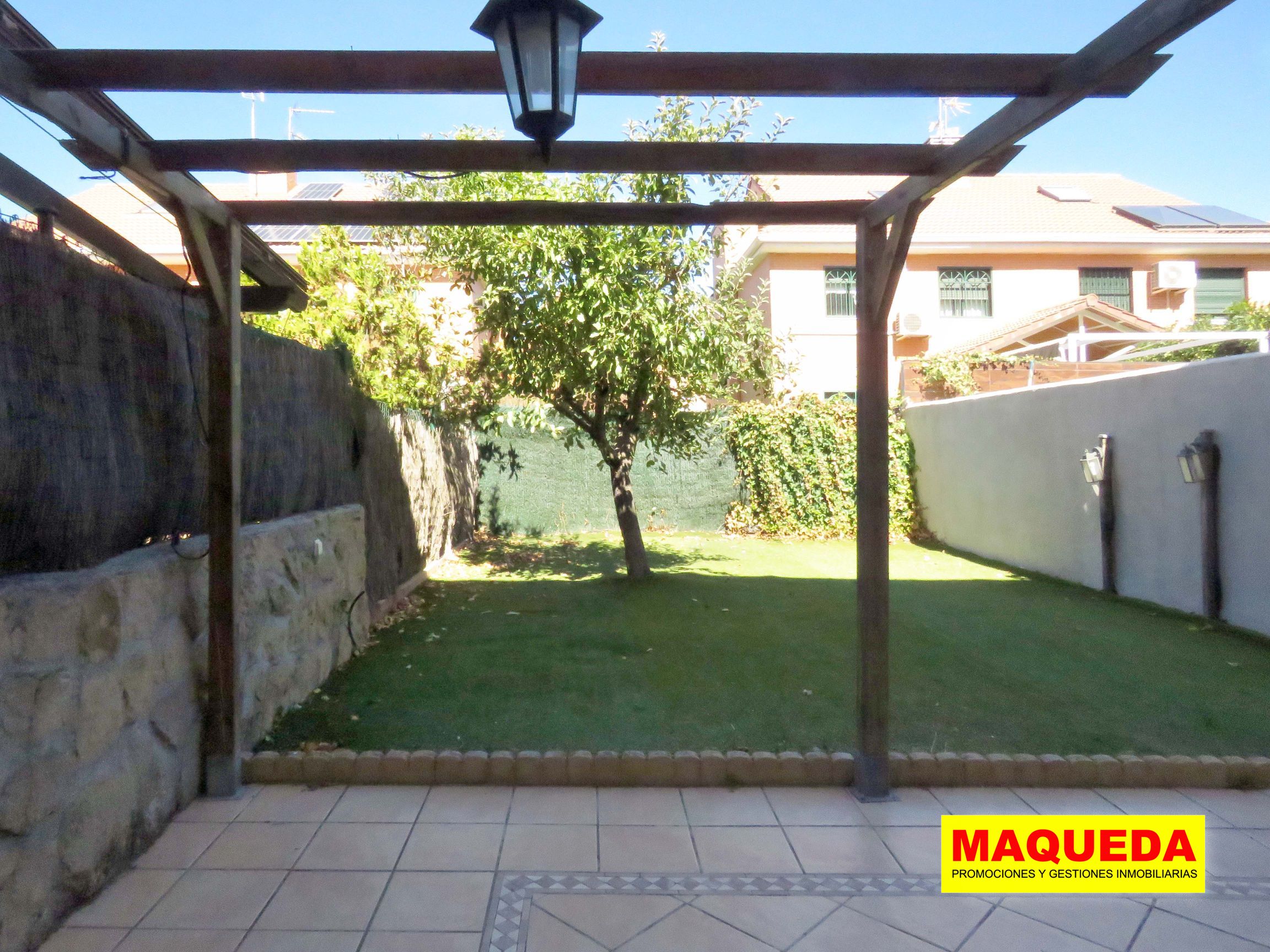 Jardín con pérgola de madera, césped artificial y árbol frutal