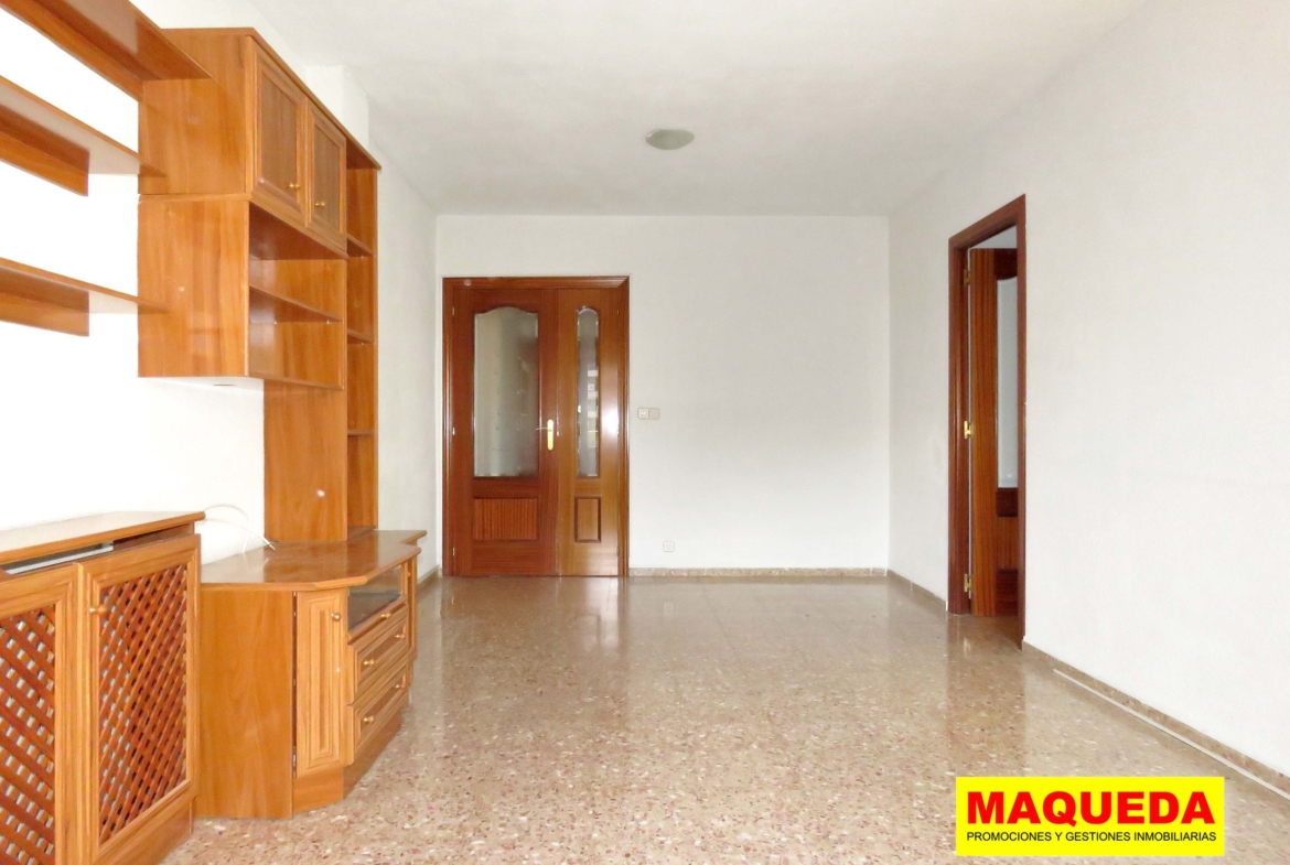 Vista del salón - comedor desde la terraza. A la izquierda mueble librería, al fondo puerta de acceso y a la derecha pasillo de distribución a los dormitorios