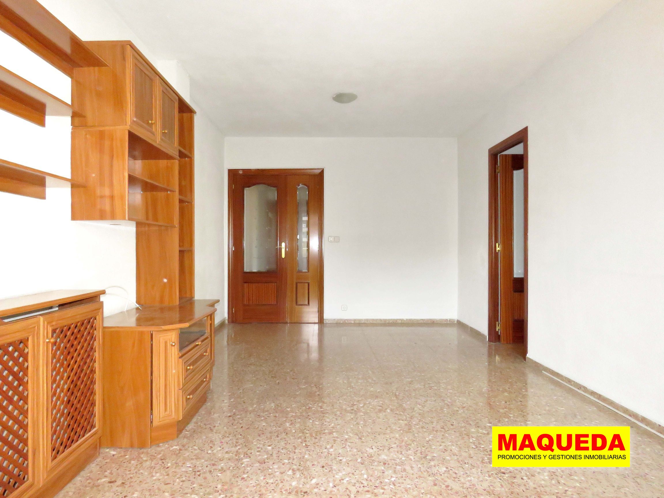 Vista del salón - comedor desde la terraza. A la izquierda mueble librería, al fondo puerta de acceso y a la derecha pasillo de distribución a los dormitorios