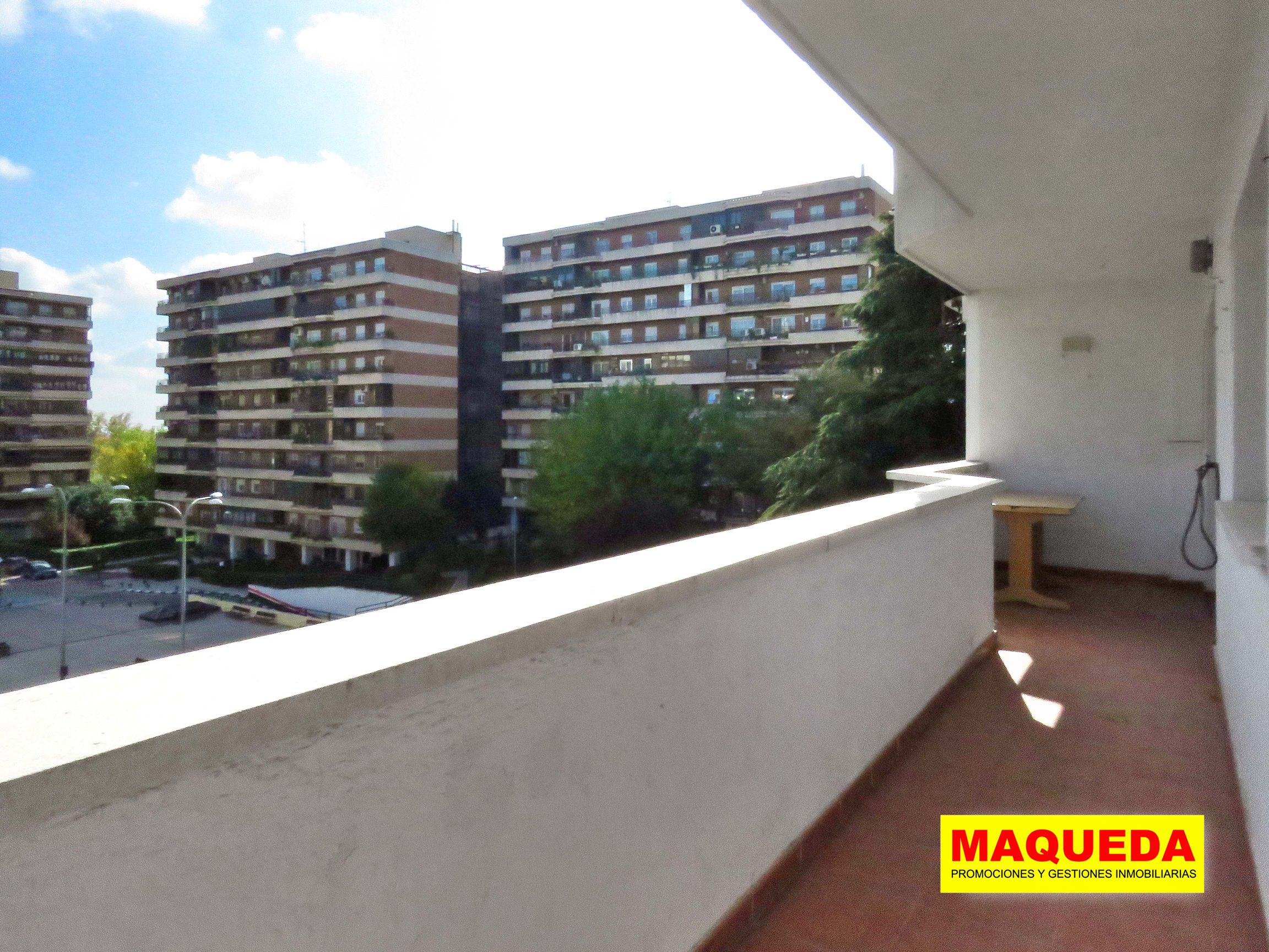 Terraza abierta con zona amplia para mesa y sillas al fondo. A la izquierda plaza de Residencial Igueldo con edificios de viviendas